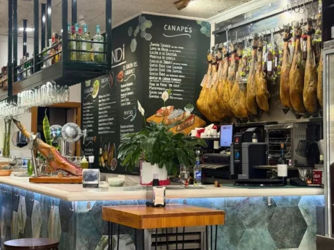 Barra de La Taberna de Buendi con pizarra de canapés y jamones colgados